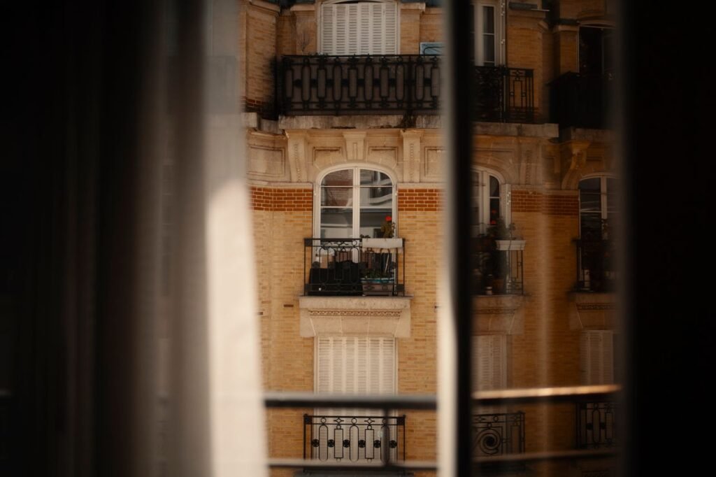 View of classical city apartment building through a window, capturing urban architecture.