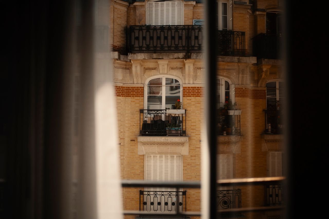 View of classical city apartment building through a window, capturing urban architecture.